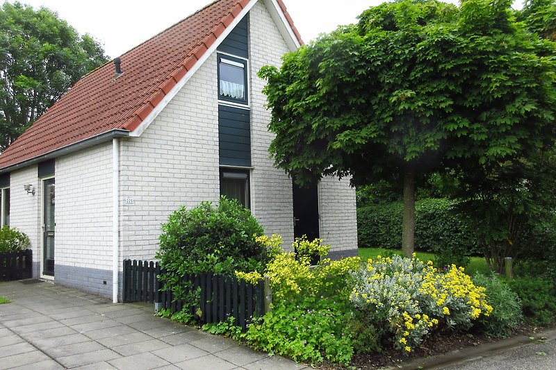 Gemütliches Haus mit Garten, Hecke und Einfahrt in ruhiger Vorstadt.