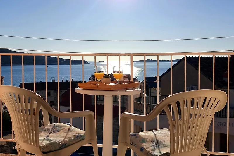 Balkon mit Meerblick, Outdoor-Möbeln und Pflanzen.