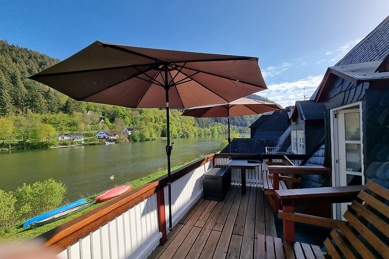 Blick auf den See vom Balkon mit Tisch und Stühlen.