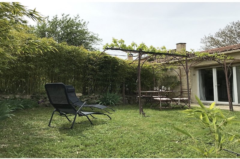 Garten mit Pergola, Möbeln und gepflegtem Rasen.