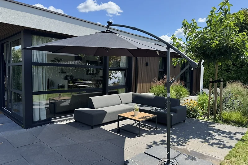 Garten mit Pergola, Gartenmöbeln und Sonnenschirm.