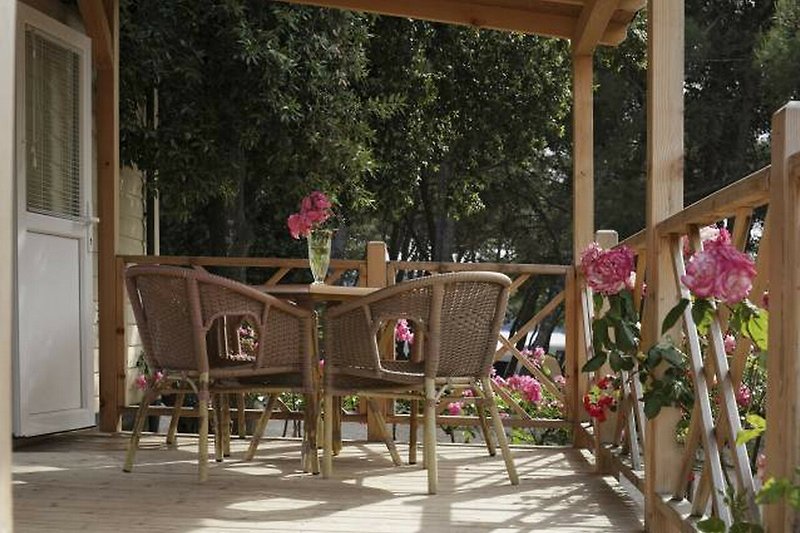 Entspannte Terrasse mit Holzstühlen und Pergola im Grünen.