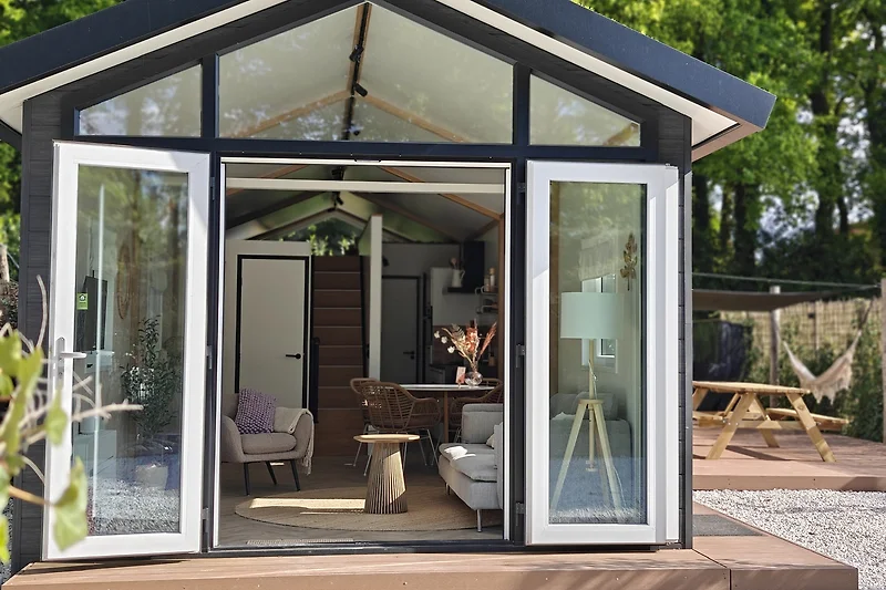 Eingang mit Holzverkleidung, Gartenhaus und mobilem Tiny House.