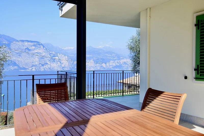 Meerblick von der Terrasse mit Holzmöbeln und Pflanzen.