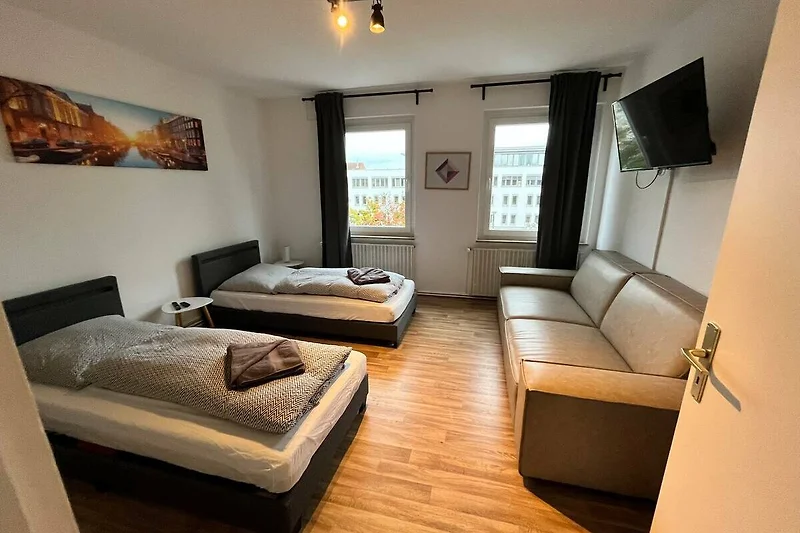 Gemütliches Schlafzimmer mit einladendem Bett und stilvoller Bettwäsche. TV und Couch