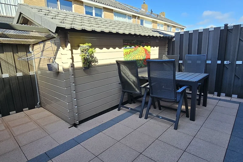 Grote tuin met terras, houten terras en tuinmeubelen.