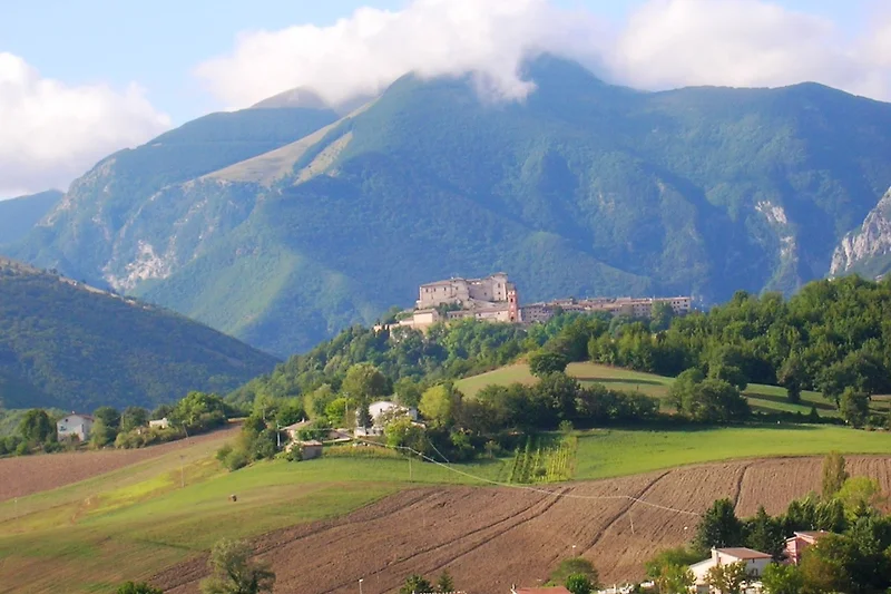 Berglandschaft mit Talblick und malerischem Dorf im Hintergrund.