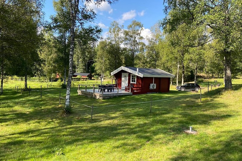 Grüner Garten mit Rasen, Bäumen und einem rustikalen Holzhaus.