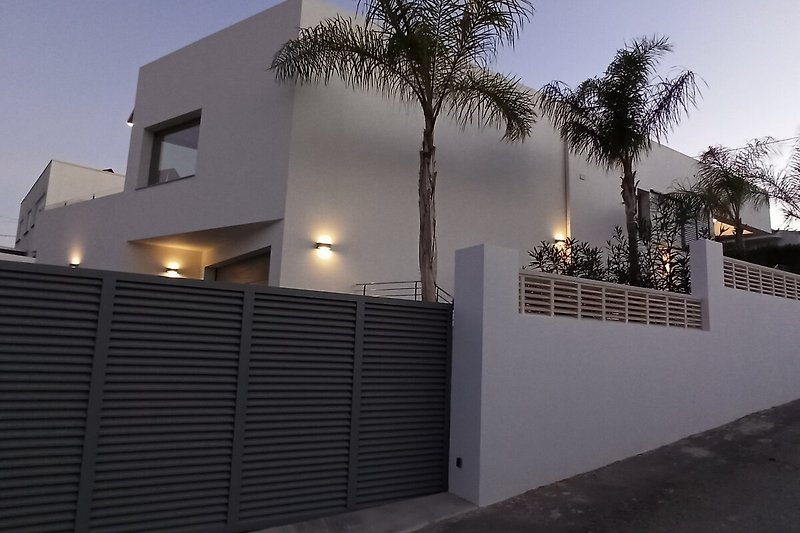 Villa mit Balkon, Tor und Palmen im sonnigen Kalifornien.