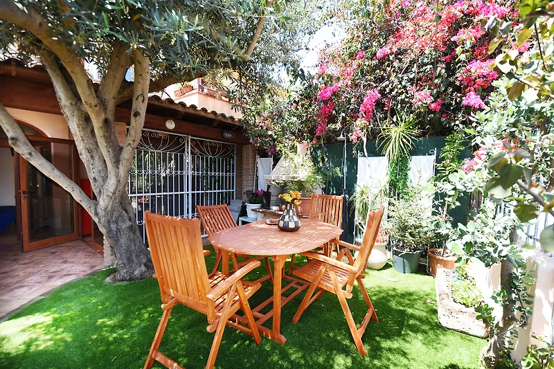 Garten mit Outdoor-Möbeln, Pflanzen und Blumenarrangements.