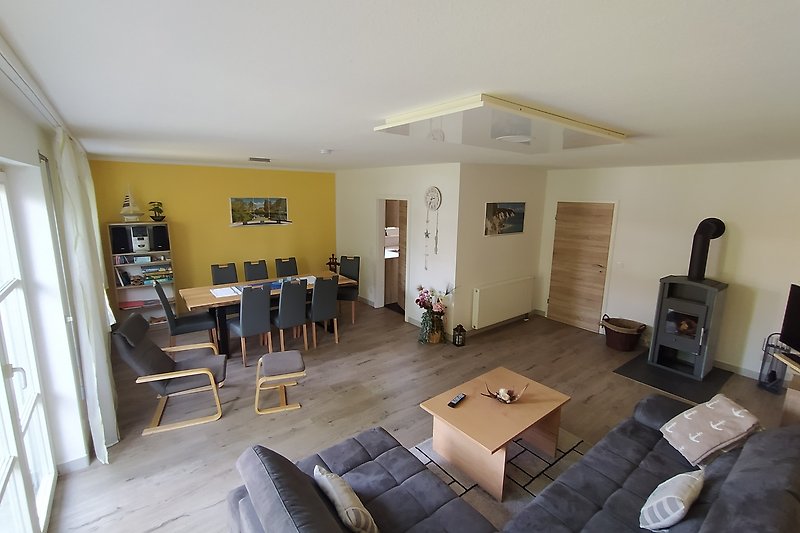 Gemütliches Wohnzimmer mit großem Esstisch Couch und Fernseher sowie Kaminofen für kühlere Tage.