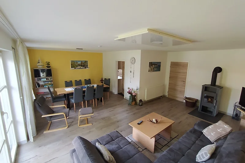 Gemütliches Wohnzimmer mit großem Esstisch Couch und Fernseher sowie Kaminofen für kühlere Tage.