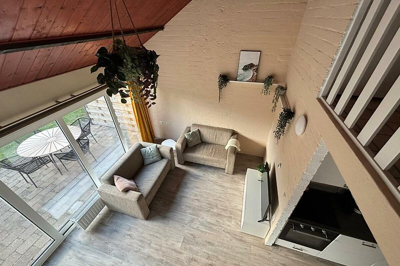 Helles Wohnzimmer mit Holzdecke und bequemer Couch.