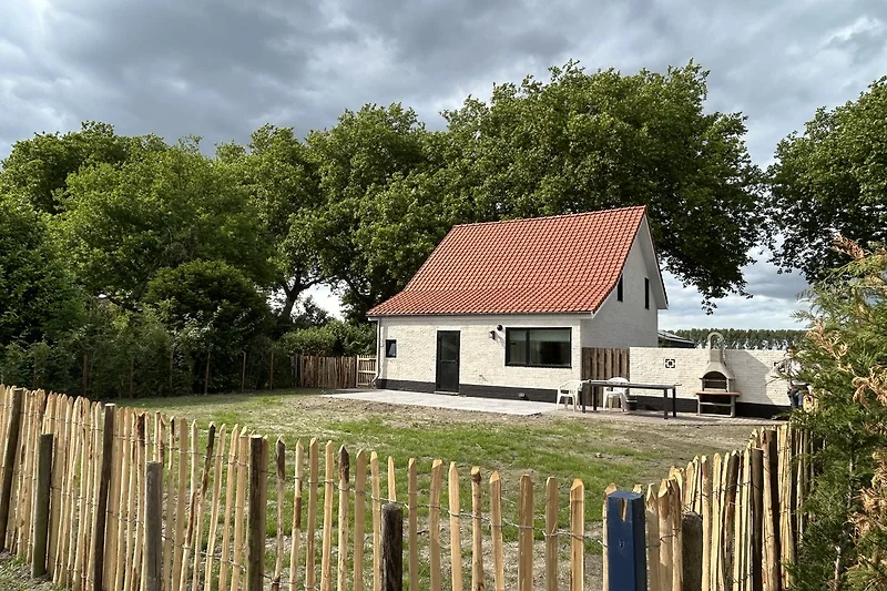 Ländliches Haus mit Garten und Zaun im Dorf.
