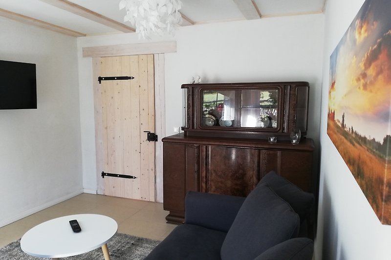Wohnzimmer mit grauem Sofa, Fernseher und Holzmöbeln.