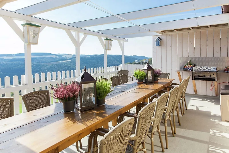 Veranda mit Tisch, Stühlen und Pergola im Freien.