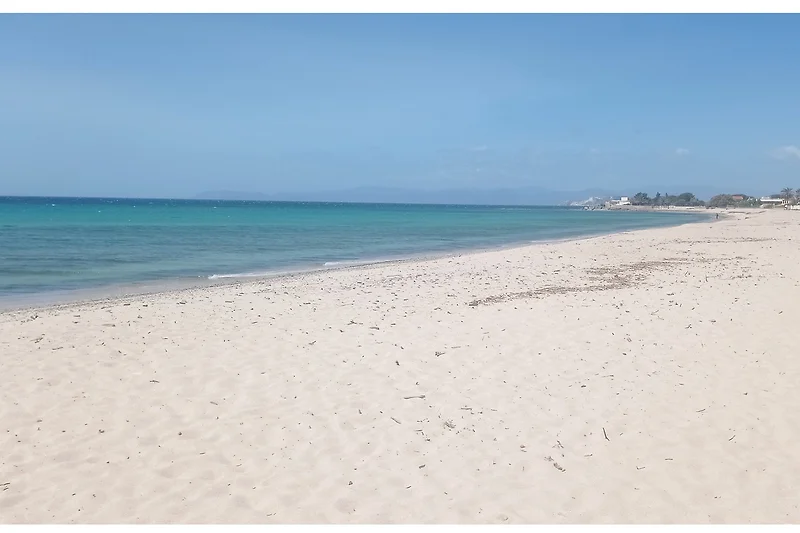 Traumhafter Strand mit türkisblauem Meer und sanften Wellen.