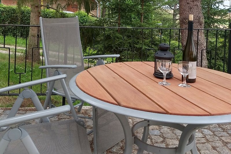 Gemütliche Terrasse mit Holzmöbeln und Pflanzen im Garten.