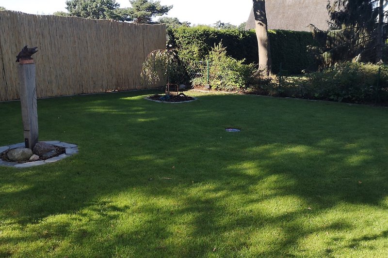 Grüner Garten mit gepflegtem Rasen und schattigem Bereich.