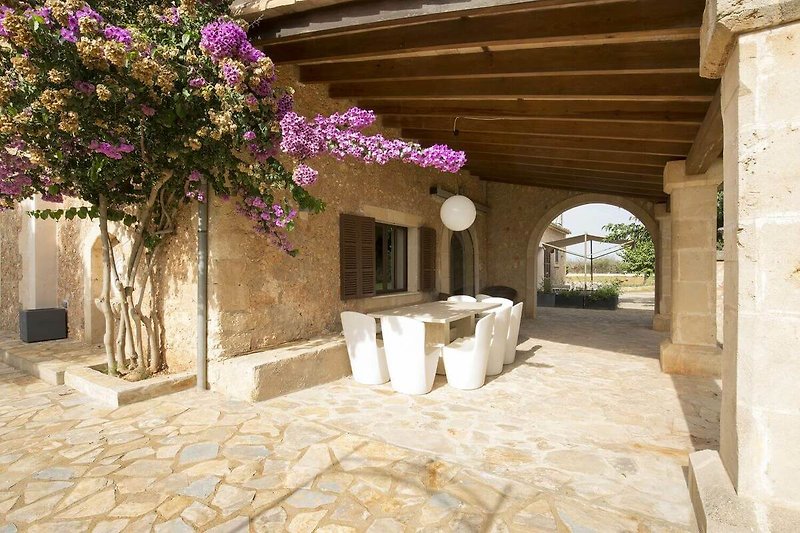 Helle Villa mit Arkaden, Blumen und Pflanzen im Innenhof.