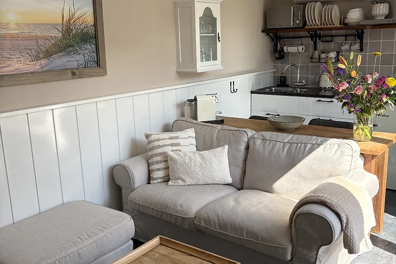Wohnzimmer mit grauem Sofa, Kissen und stilvoller Beleuchtung.