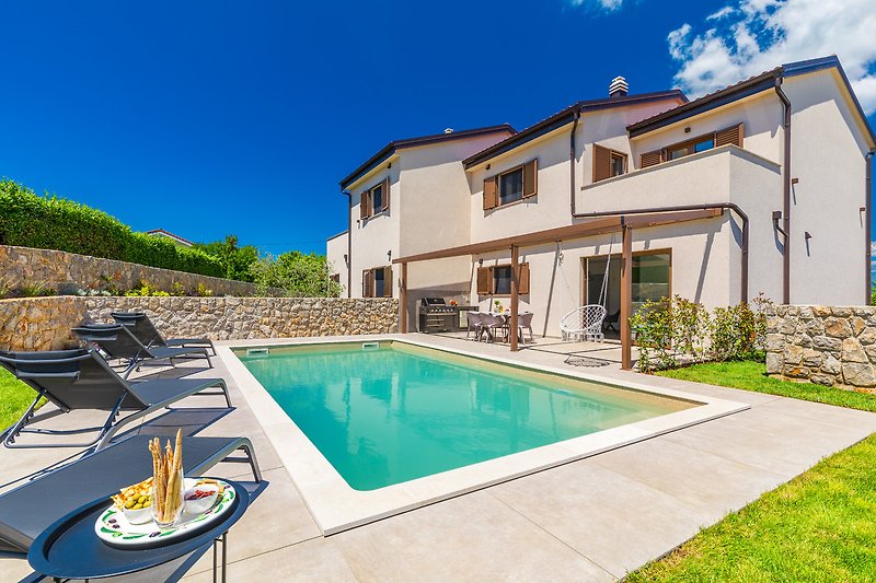 Villa mit Pool, Liegestühlen und gepflegtem Garten.