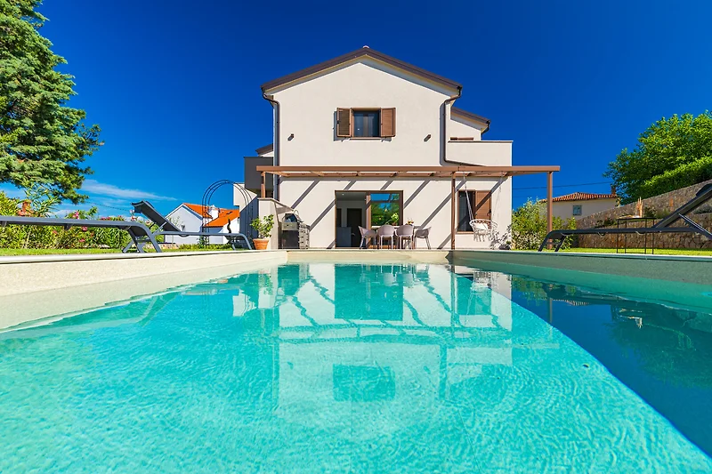 Villa mit Pool, Wasserfall und üppiger Landschaft.
