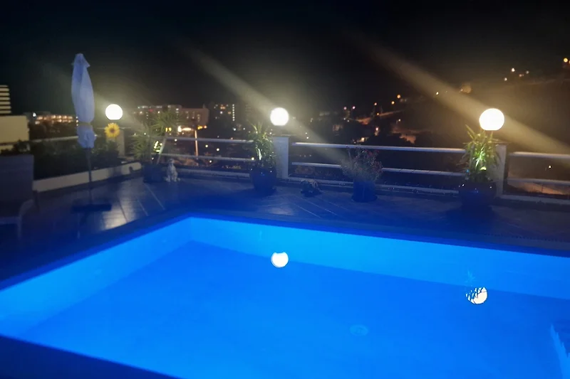 Der beheizte Pool mit bequemer Treppe bei Nacht.