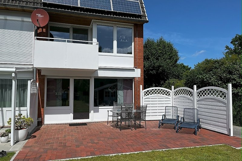 Einladende Terrasse mit Blumen und gemütlicher Sitzgelegenheit.