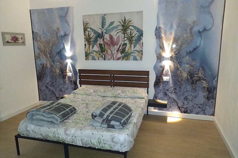 Gemütliches Schlafzimmer mit Holzfußboden, stilvoller Beleuchtung und eleganter Bettwäsche.