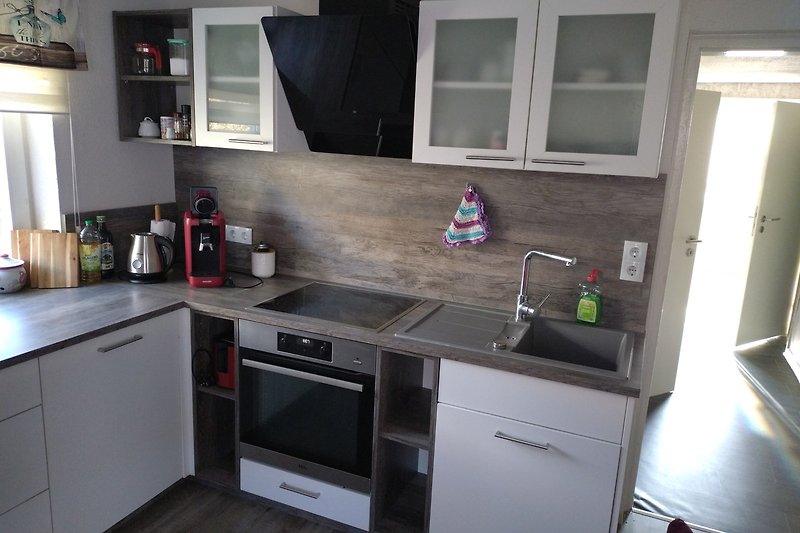 Moderne Küche mit Geräten, Granit-Arbeitsplatte und Holzschränken.