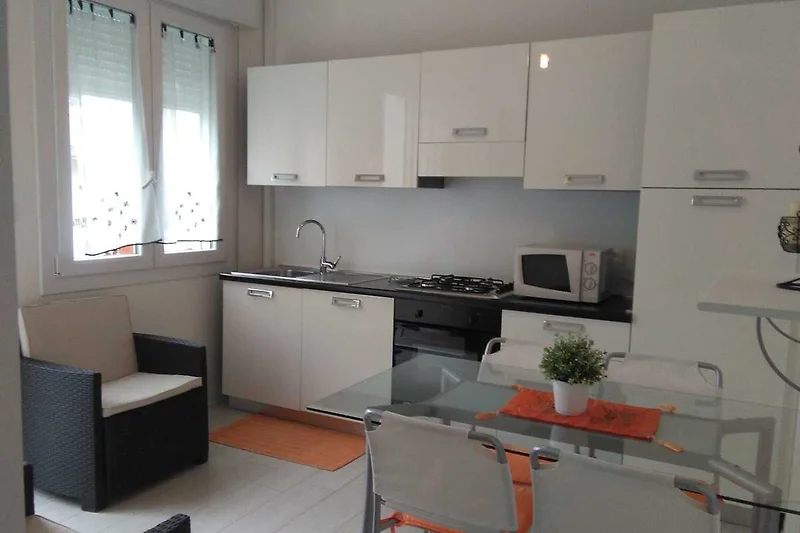 Voll ausgestattete Küche mit Holzdetails, großem Tisch und Sofa.