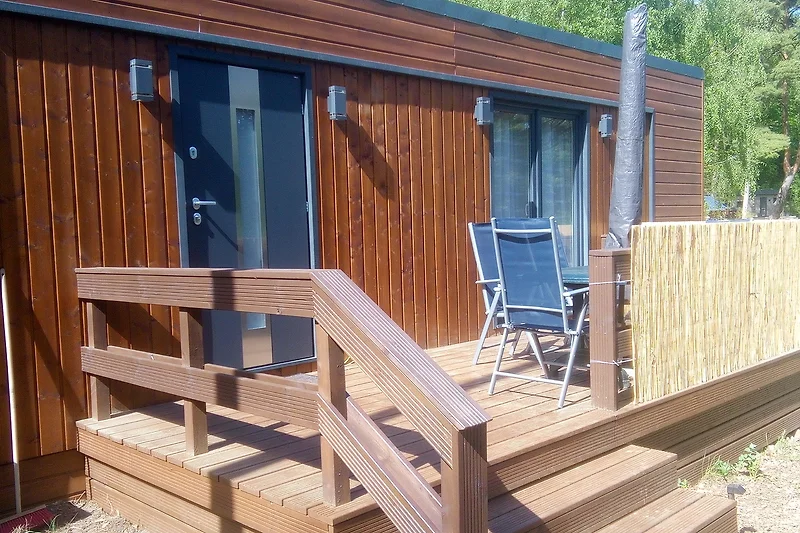 Große Terrasse mit Liegestühlen, Sesseln, Tisch und Sonnenschirm mit viel Sonne