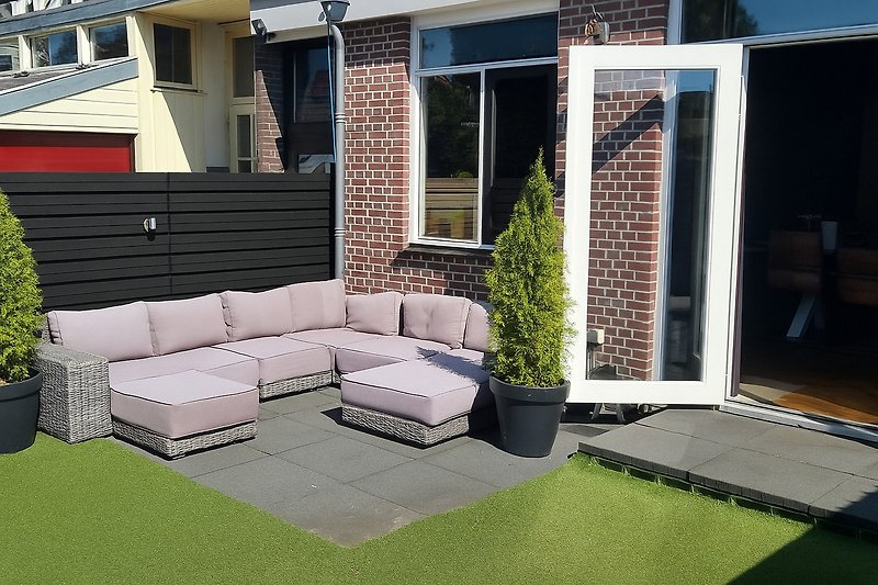 Gepflegter Garten mit stilvollen Möbeln und blühenden Pflanzen.