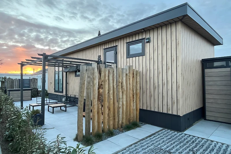 Holzverkleidung, robuste Tür und überdachte Terrasse im Innenhof.