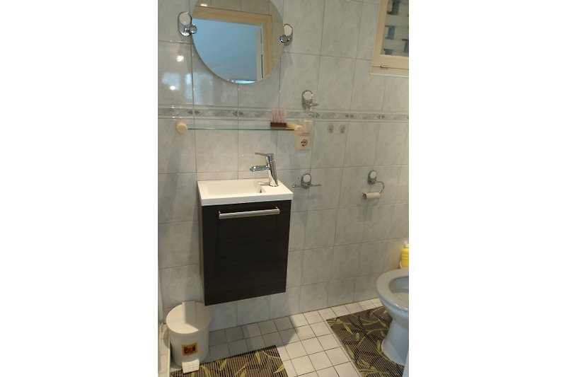 Moderne badkamer met glazen douchecabine en metalen kranen.
