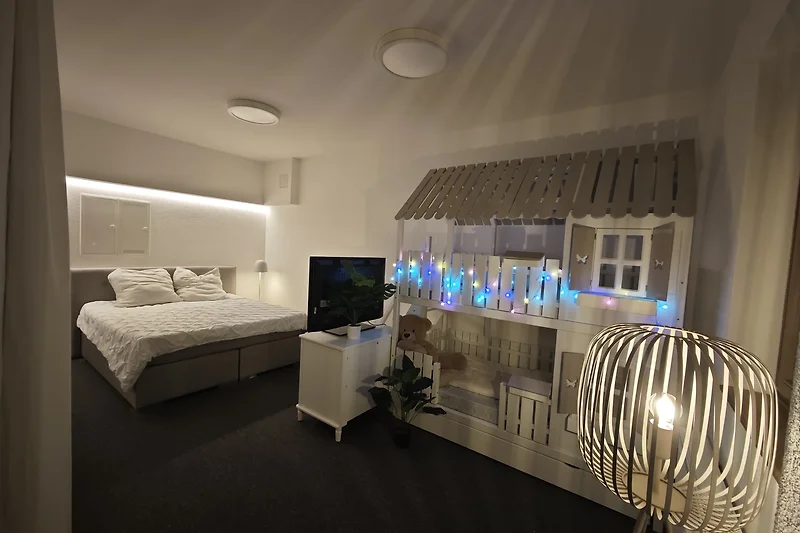 Familien-Schlafzimmer mit King-Size Boxspringbett, Stockbett für Kinder zum Schlafen und Spielen, Spielsachen, TV.