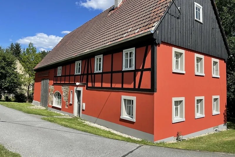 Traditionelles Bauernhaus mit Sprossenfenstern und Scheune.