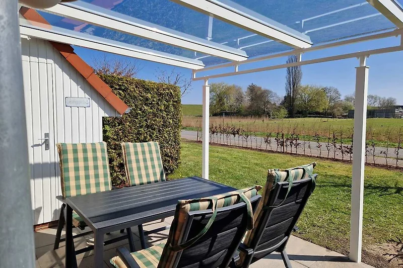 Garten mit Pergola, Gartenmöbeln und Sonnenschutz.