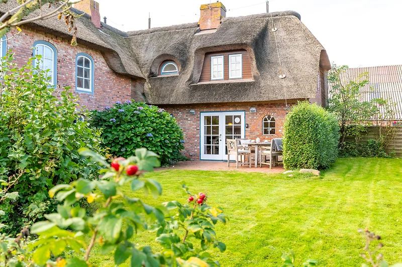 Historisches Landhaus mit Reetdach, gepflegtem Garten und Einfahrt.