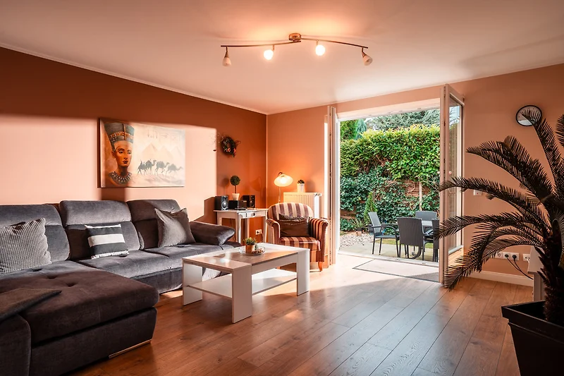 Großzügiger Wohnbereich mit Sofa, Fernseher, Esstisch und Pflanzen.