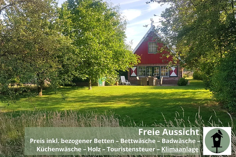Weitläufiges Grundstück mit Bäumen, Wiese und traditionellem Haus.