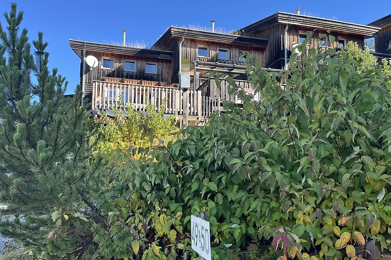 Balkon mit Blick auf grüne Fichten und das traditionelle Gasthaus.