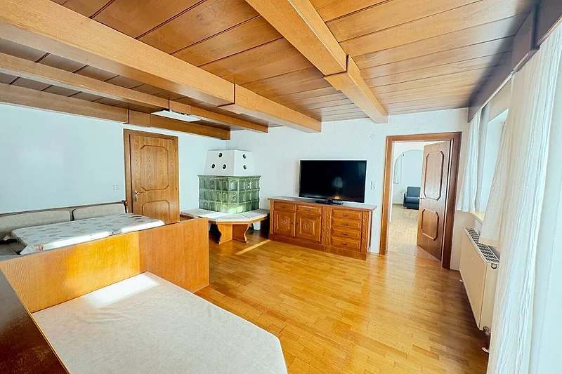 Offener Wohnbereich mit Holzplanken, Couch, Sessel und TV-Wand.