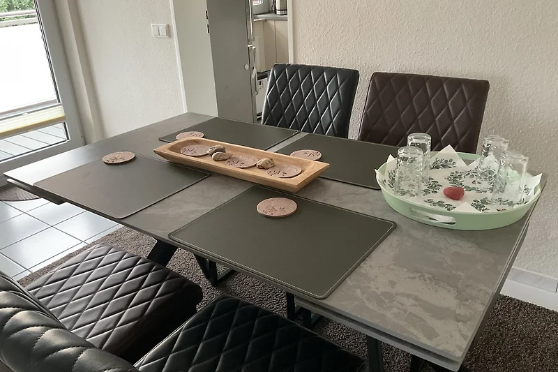 Marmor-Tisch mit Servierplatte, Besteck, Küchenutensilien und Pflanze.