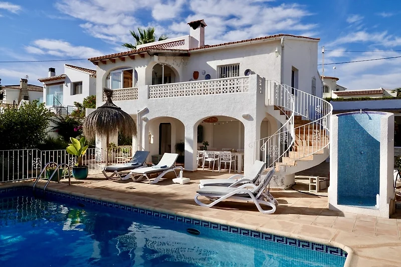 Villa mit Pool, Sonnenliegen, Palmen und stilvoller Außengestaltung.
