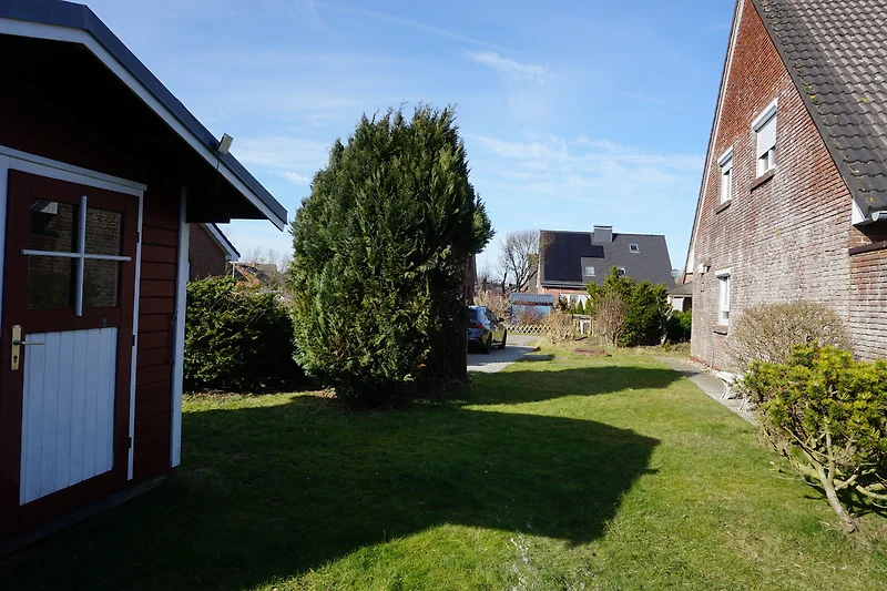 Freistehendes Haus mit gepflegtem Vorgarten, Einfahrt und Gartenhaus.