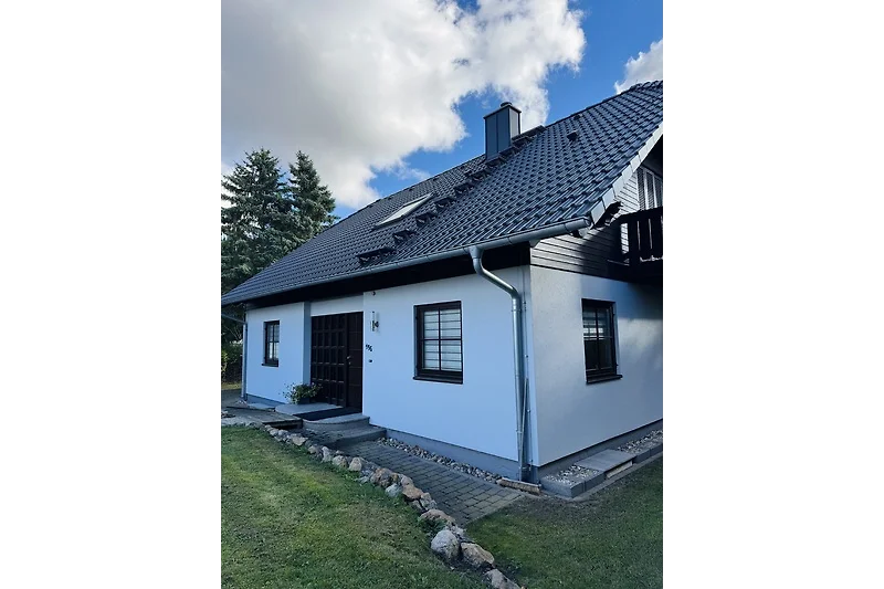 Graues Landhaus mit Sprossenfenstern, Tür, Einfahrt und Garten.