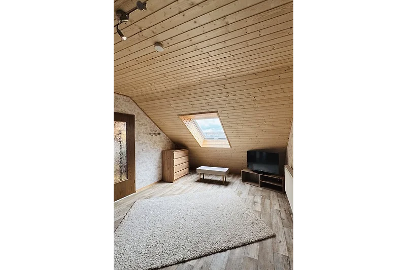 Holzdecke, sichtbare Balken und viel Tageslicht im Dachgeschoss.