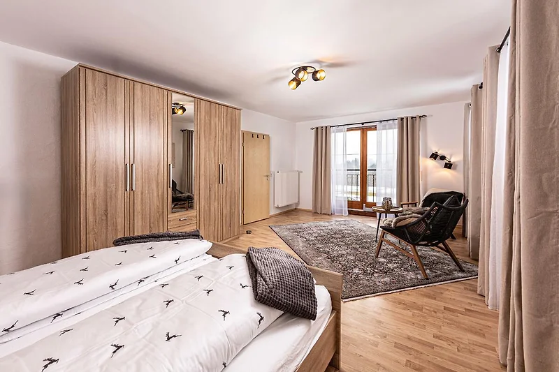 Komfortables Schlafzimmer mit Doppelbett, Schrank und Fenster.